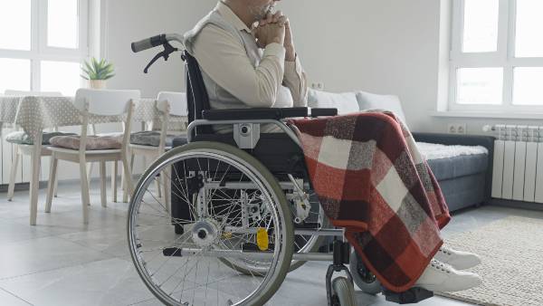 An elderly nursing home resident sits alone in a wheelchair